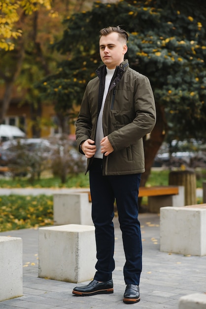 Portrait of a young handsome man, model of fashion, with modern hairstyle in urban background, wearing casual clothes.