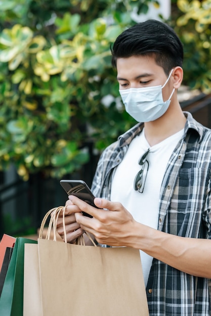 Portrait Young handsome man in protection mask holding paper bag