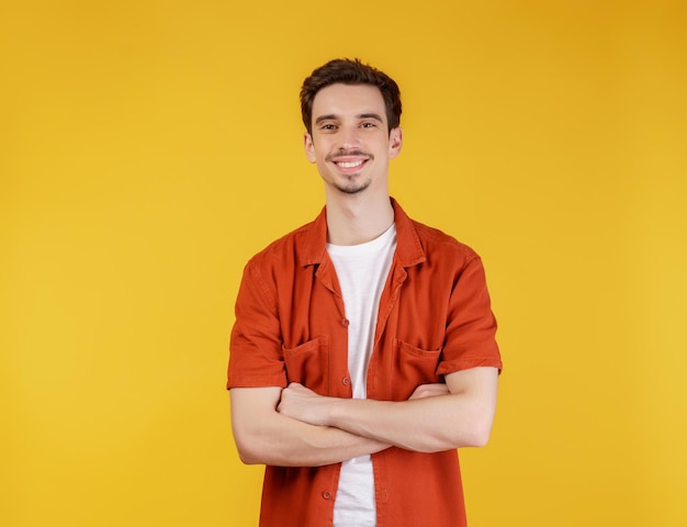 Portrait of young handsome man standing with crossed arms with isolated on studio yellow background