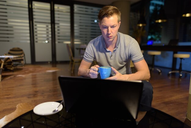 portrait of young handsome man using laptop in the living room