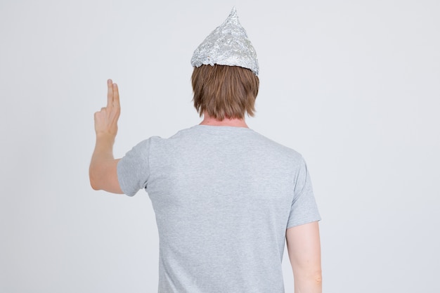 portrait of young handsome man wearing tin foil hat as conspiracy theory concept on white