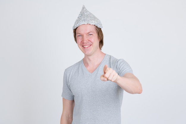 portrait of young handsome man wearing tin foil hat as conspiracy theory concept on white