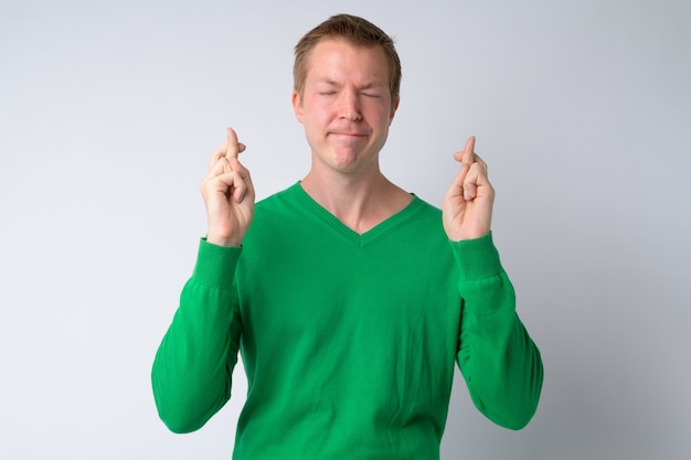 Portrait of young handsome man wishing with fingers crossed