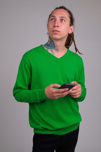 Portrait of young handsome man with dreadlocks against white wall