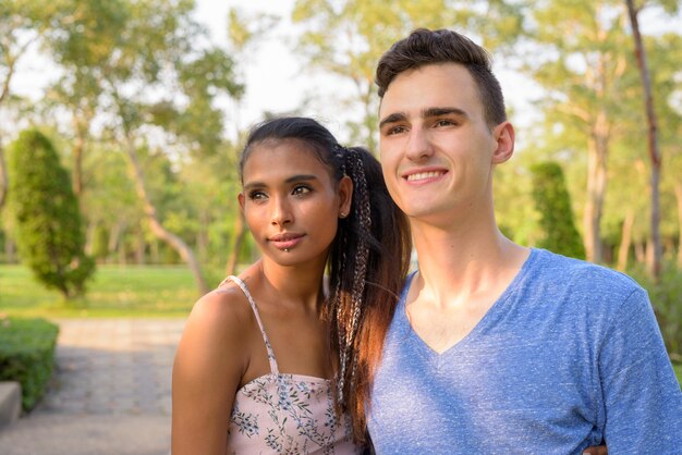 Photo portrait of young handsome man and young beautiful asian woman relaxing together at the park