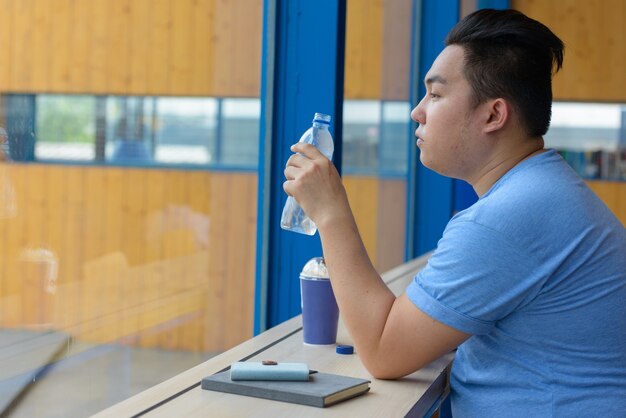 Portrait of young handsome overweight Filipino man relaxing at the coffee shop