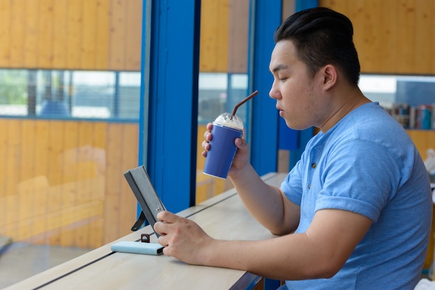 Portrait of young handsome overweight Filipino man relaxing at the coffee shop