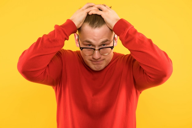 Portrait of young handsome puzzled tired astonished guy under stress on yellow 