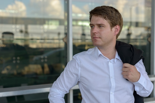 Portrait of young handsome Scandinavian businessman at the airport in the city