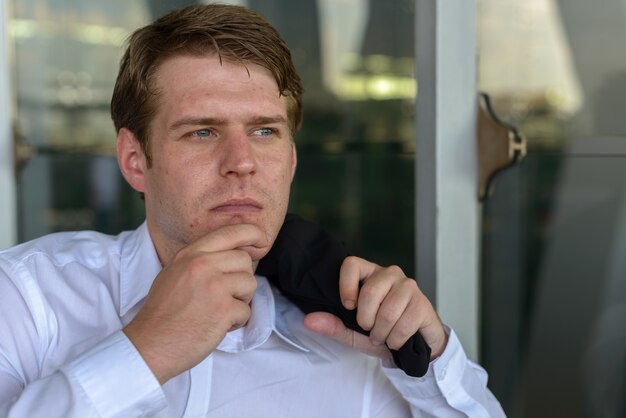 Portrait of young handsome Scandinavian businessman at the airport in the city