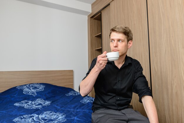 Portrait of young handsome Scandinavian businessman with blond hair at home indoors