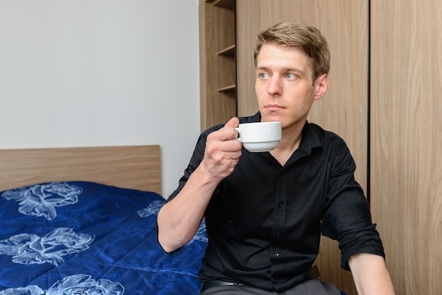 Portrait of young handsome Scandinavian businessman with blond hair at home indoors