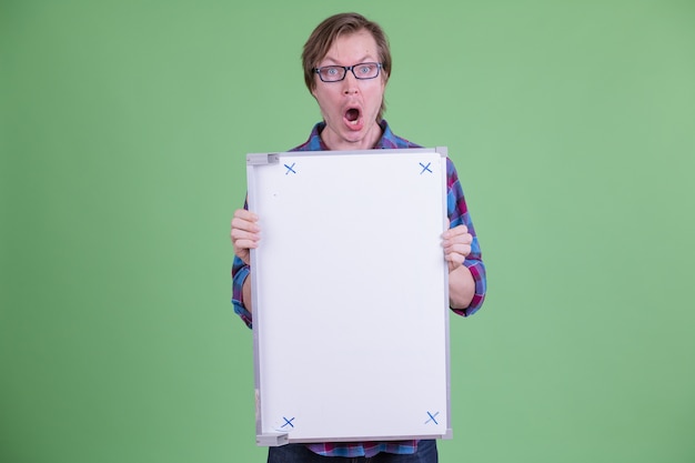 Portrait of young handsome Scandinavian hipster man with eyeglasses against chroma key or green wall