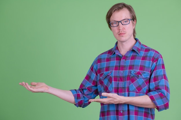 Portrait of young handsome Scandinavian hipster man with eyeglasses against chroma key or green wall