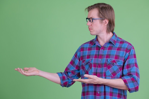 Portrait of young handsome Scandinavian hipster man with eyeglasses against chroma key or green wall