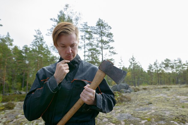 Ritratto di giovane uomo scandinavo bello pronto per la raccolta nella foresta all'aperto