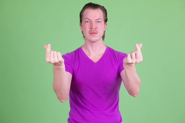 Портрет молодого красивого скандинавского мужчины в фиолетовой рубашке на фоне цветного ключа или зеленой стены