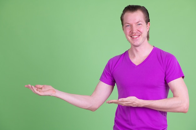 Portrait of young handsome Scandinavian man wearing purple shirt against chroma key