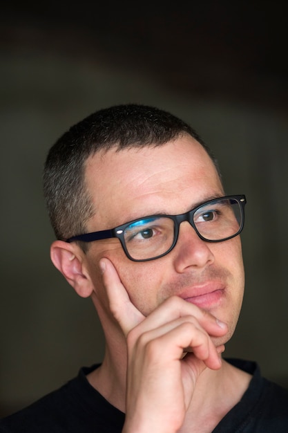 Portrait of young handsome serious black-haired confident successful intellectual man in glasses.