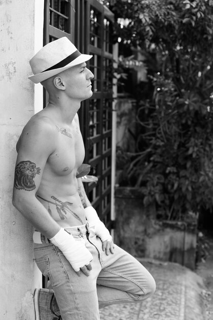 Portrait of young handsome shirtless man as fighter in the streets outdoors in black and white