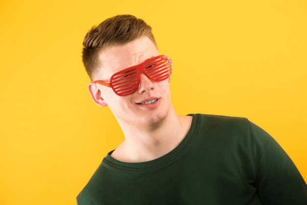 Portrait of young handsome smiling guy with sunglasses  yellow  