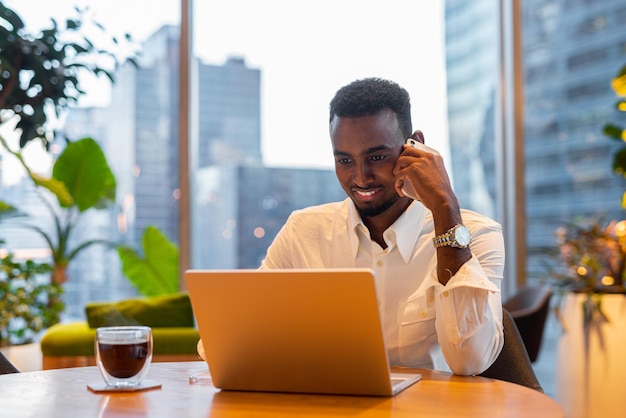 Портрет молодого красивого стильного чернокожего мужчины с ноутбуком в кафе