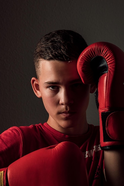 Portrait of a young handsome teenage boxer in red gloves