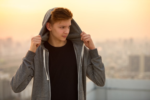 Portrait of young handsome teenage boy against view of the city outdoors