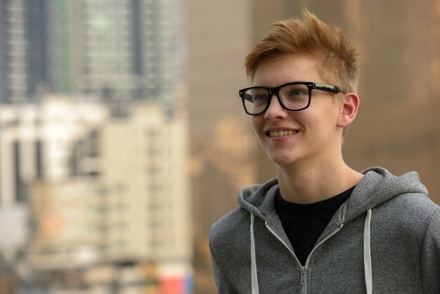 Portrait of young handsome teenage boy against view of the city outdoors