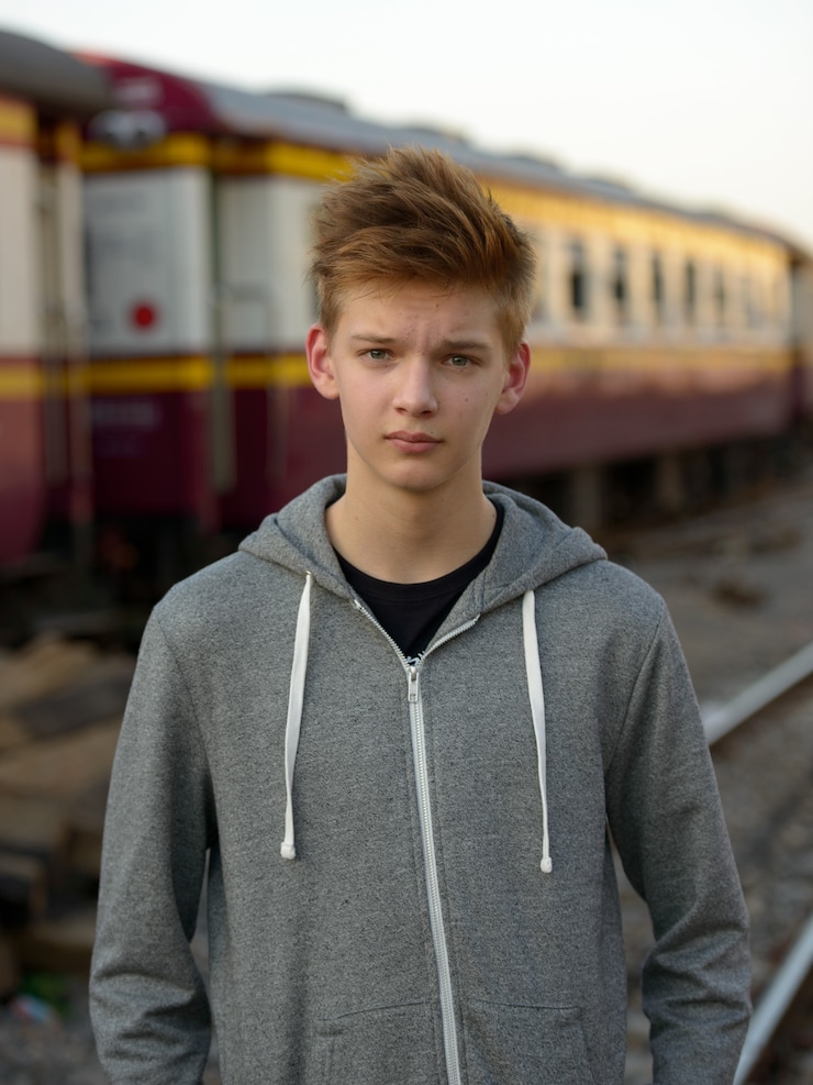 Photo portrait of young handsome teenage boy at the railway train station