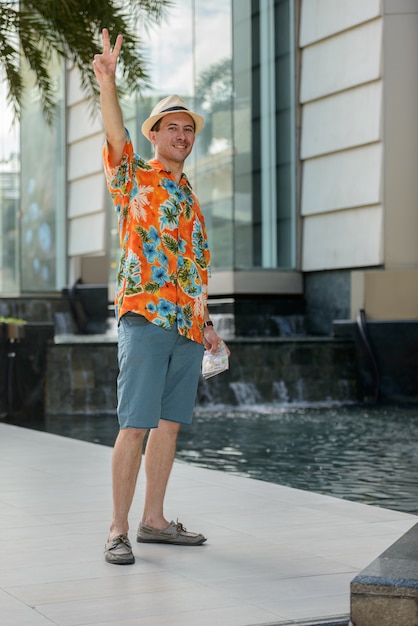 Portrait of young handsome tourist man outside shopping mall in the city