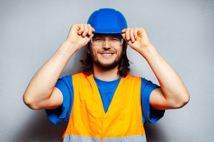 portrait of young happiness construction worker engineer wearing safety equipment; holding hard helmet with hands