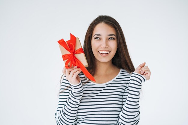 Портрет молодой счастливой азиатки с подарочной коробкой в руках на белом фоне изолирован