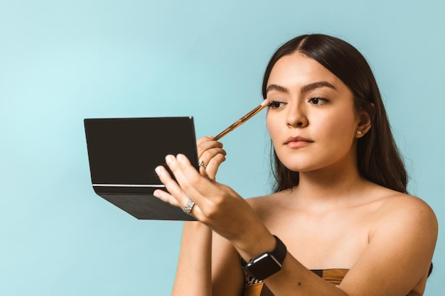 Portrait of young happy and beautiful latin American woman applying face make up