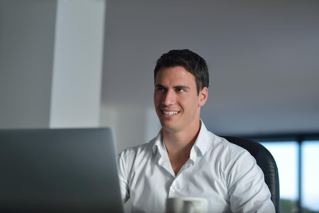 自宅のラップトップ コンピューターに取り組んでいる若い幸せなビジネスの男性の肖像画