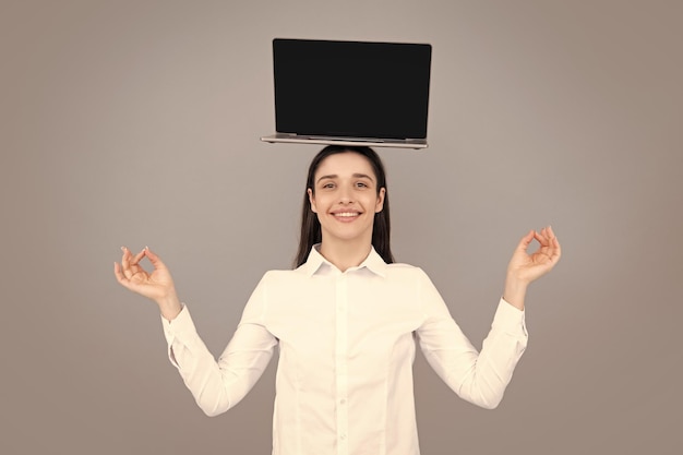 Portrait of a young happy business woman with a laptop over gray background Funny meditation