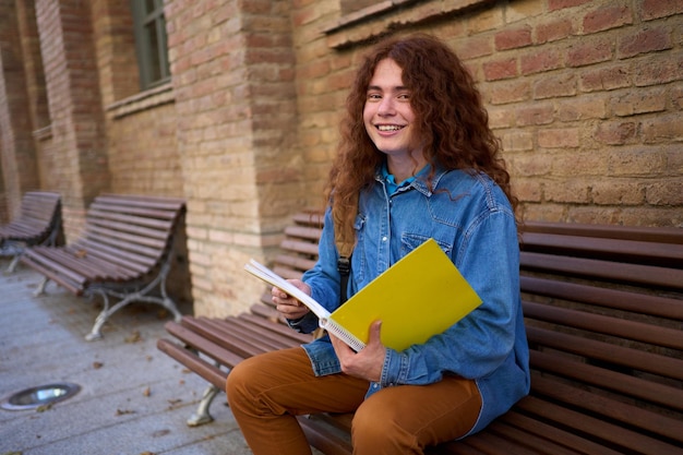 Photo portrait of young happy caucasian red head student outside the university building looking at camera