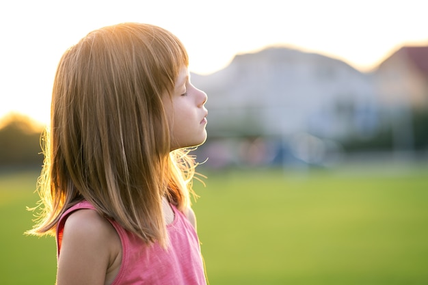 Portrait of young happy child girl relaxing outdoors on warm summer evening.