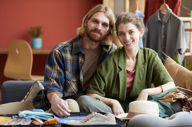 Portrait of young happy couple sitting on sofa together and smiling at camera at home