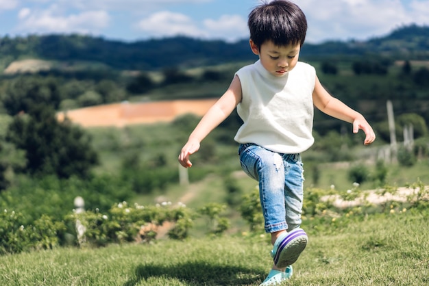Портрет молодого счастливого милого ребенка мальчика наслаждаясь и играя в природе