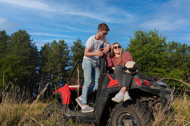 portrait of young happy excited couple enjoying beautiful sunny day while driving a off road buggy car on mountain nature
