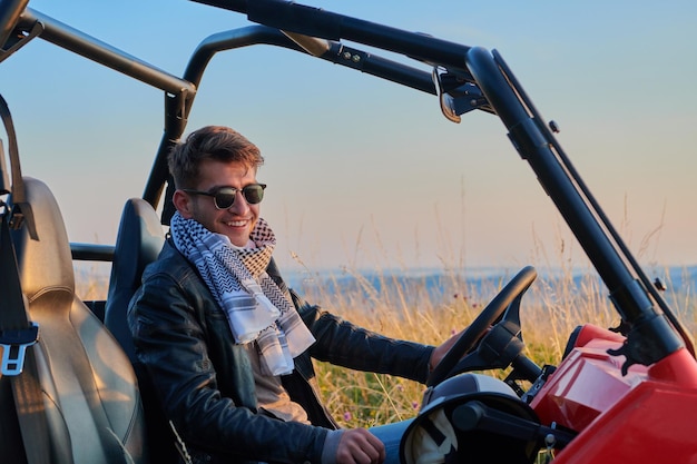 Foto ritratto di giovane uomo eccitato felice che si gode una bella giornata di sole mentre si guida un'auto buggy fuoristrada sulla natura di montagna