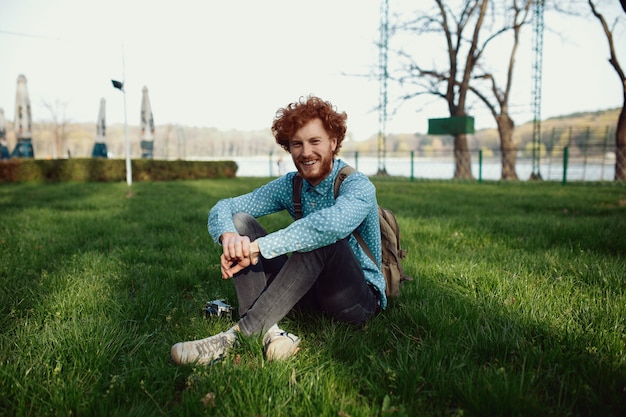 Portrait of a young happy ginger man relaxing on the grass