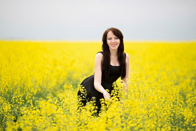 Portrait of a young happy girl in a blooming rapeseed field