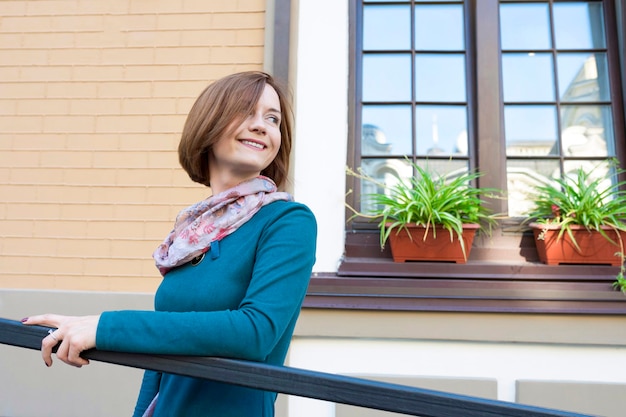 Portrait of a young happy girl outdoors against the background of a window