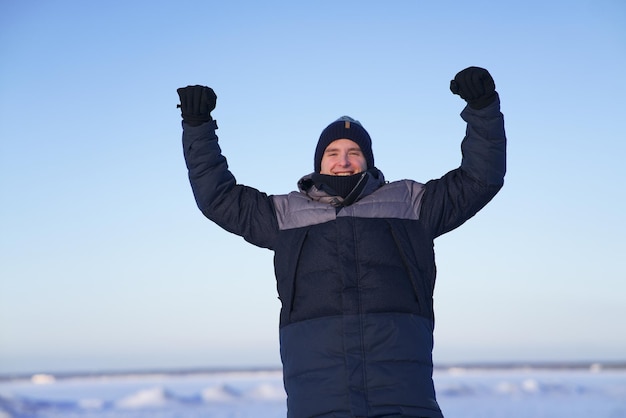 Portrait of young happy handsome man at winter snowy day smile and looking at camera