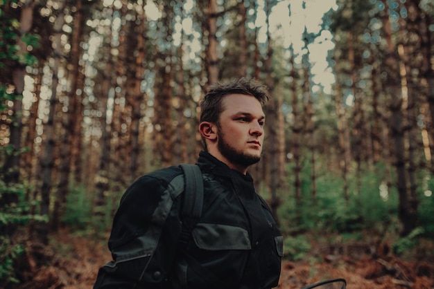 Portrait of young happy man enjoying beautiful sunny day taking a break from driving a quadatv in forest