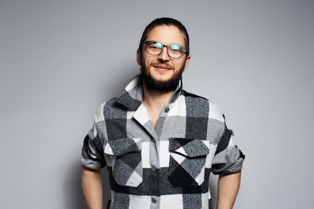 Portrait of young happy man in plaid shirt on grey background