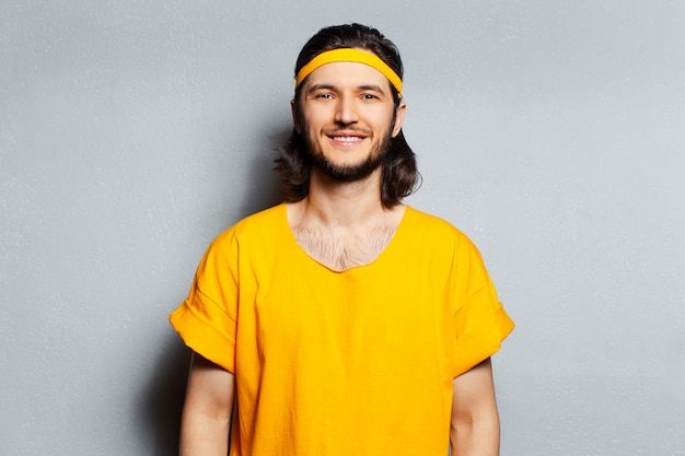 Portrait of young happy man in yellow shirt on grey background