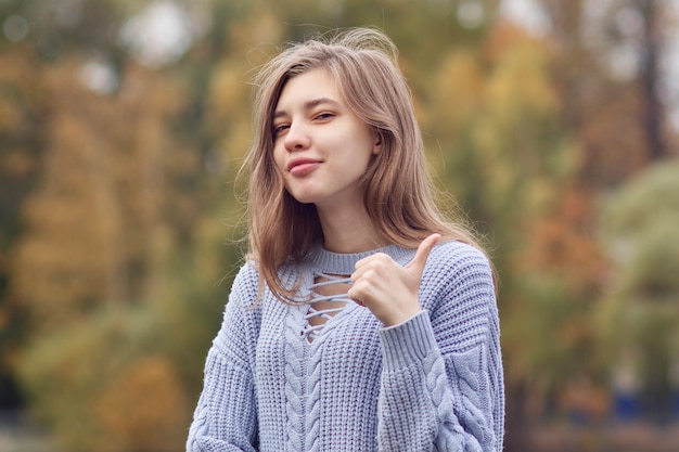 Ritratto di giovane donna positiva felice, ragazza adolescente sta mostrando il pollice in su, come, gesto di approvazione.